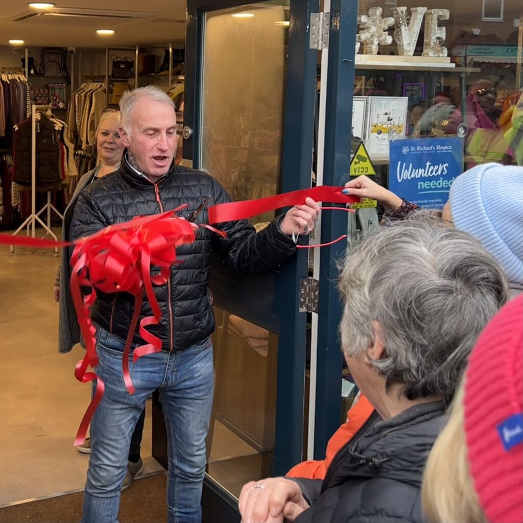 Man cuts red ribbon across door opening to mark the opening of the new shop