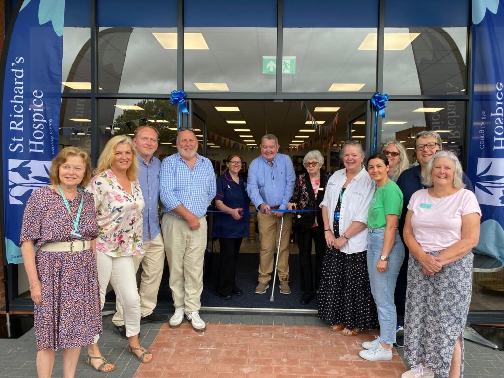 A group of people gathered for a photograph outside the hospice's superstore. Three people in the middle stand behind a ribbon, ready to cut it and officially open the store.