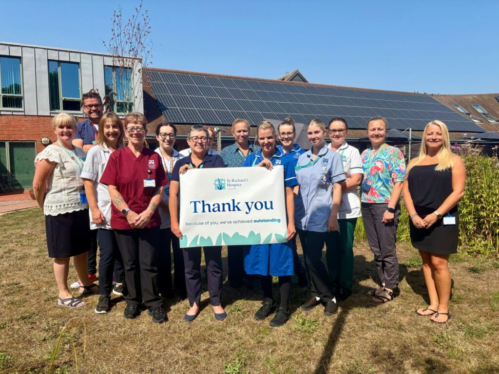 Hospice staff stand in the hospice gardens holding a banner which reads 'thank you'